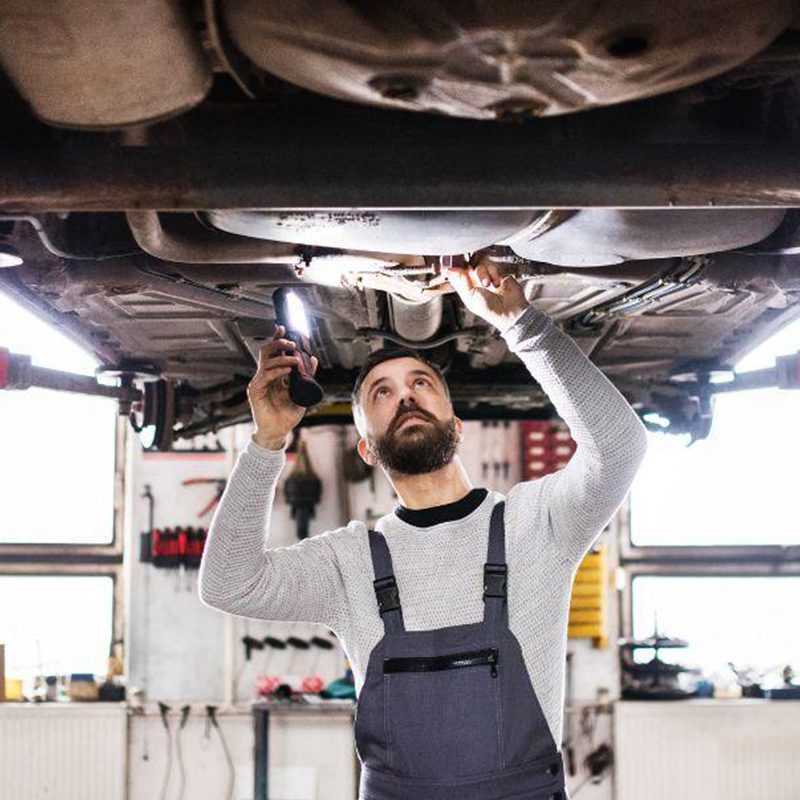 mechanic looking under car to see what needs replaced