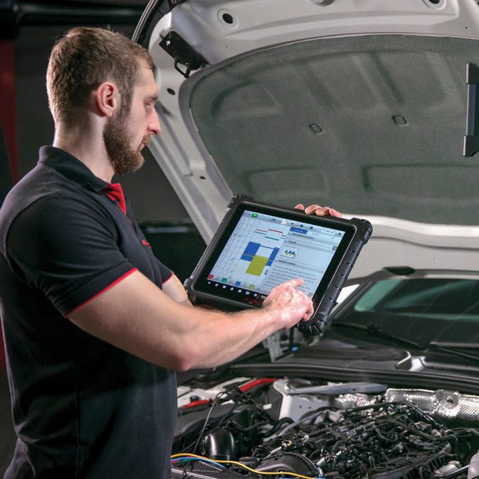 technician working on customer car using Autel diagnostic scan tool